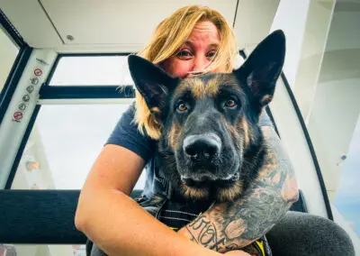 Woman smiling behind a German Shepherd service dog in ferry cabin